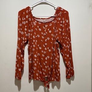 Rust colored top with white flowers and a tie. Buttons down the front